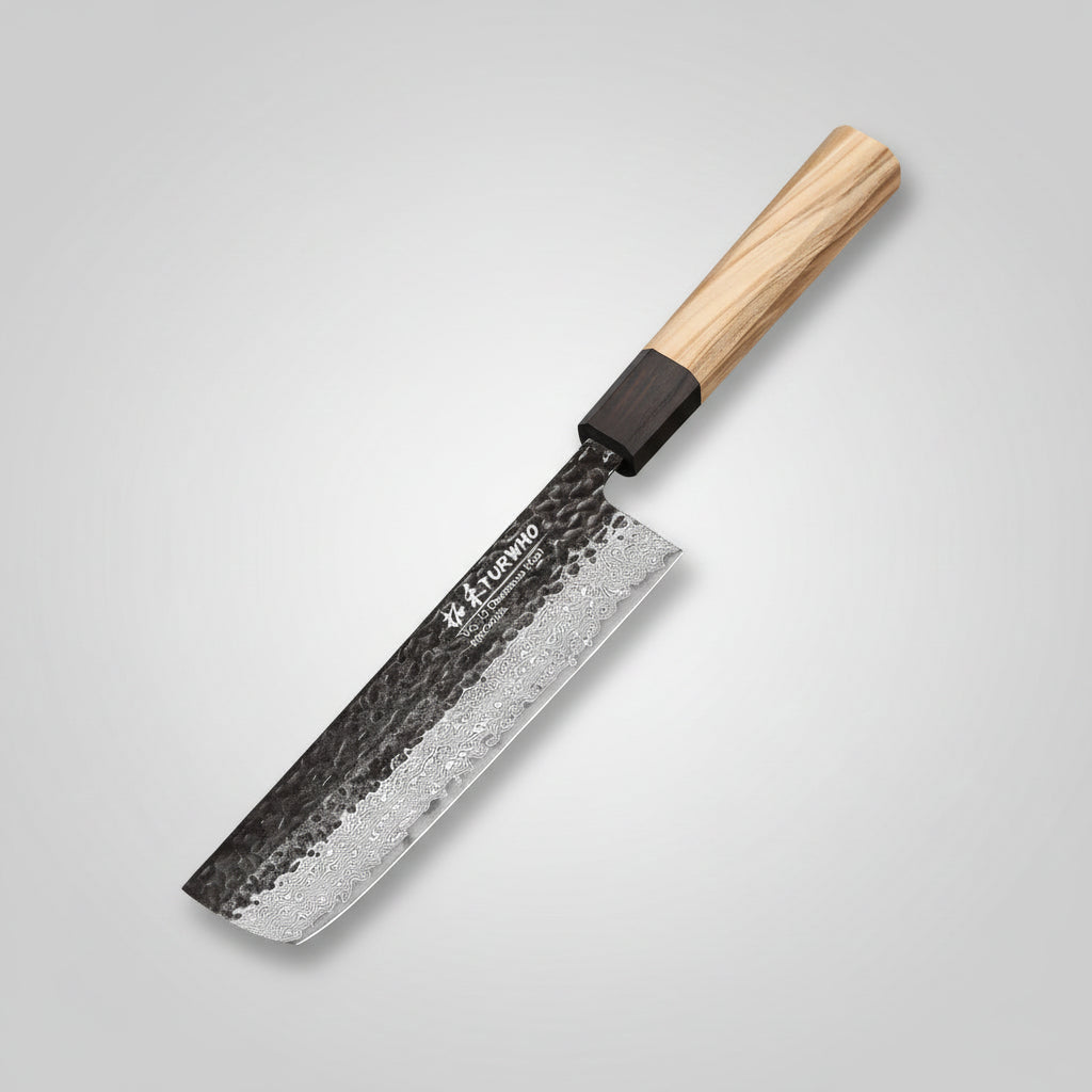 A kitchen knife with a hammered Damascus steel blade and a light wood handle, resting on a wooden cutting board with sliced red cabbage and cilantro.