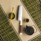 Serrated knife with wooden handle on a patterned surface with tea accessories