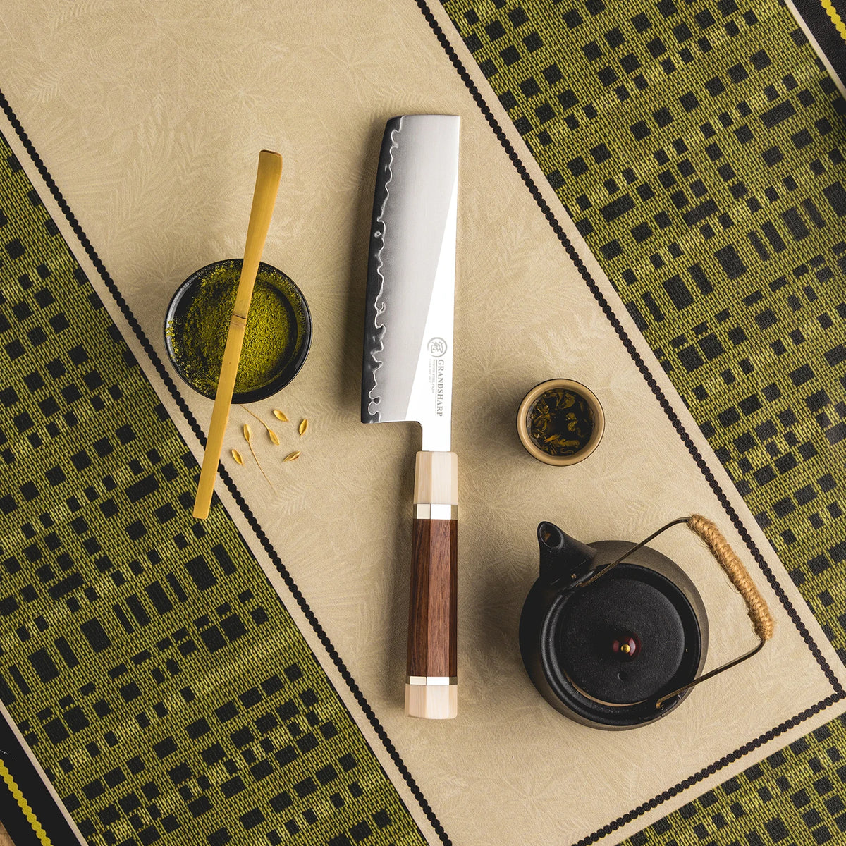 Serrated knife with wooden handle on a patterned surface with tea accessories