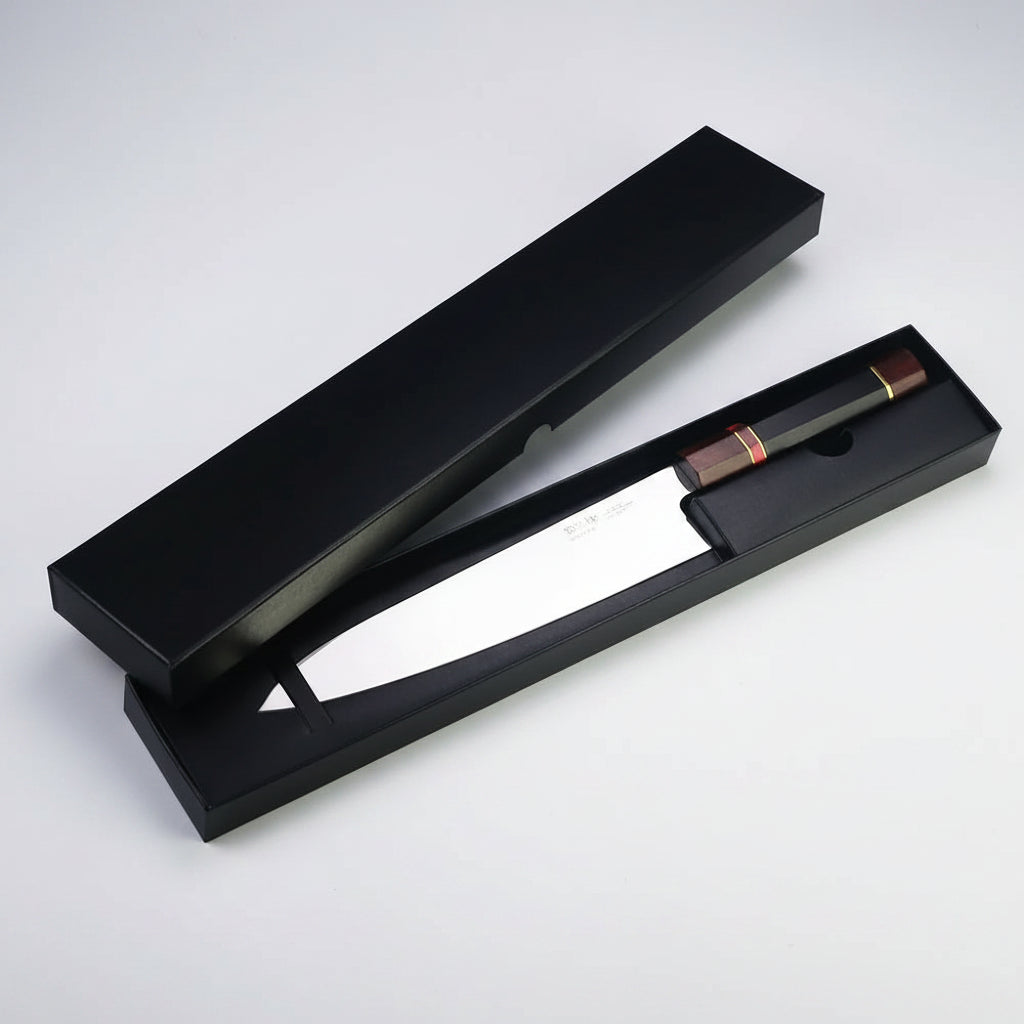 A black presentation box with its lid open, displaying a knife with a silver blade and a brown handle with red and gold accents, set against a plain white background.